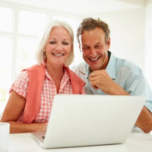 Smiling couple reviewing information on a laptop